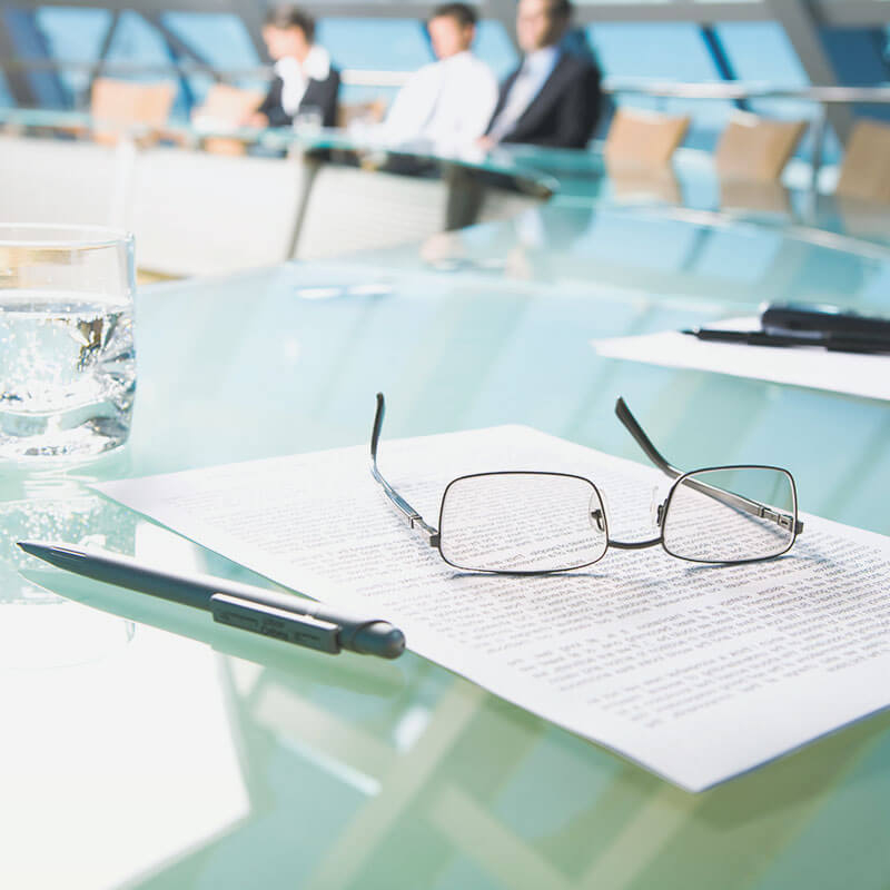 Paper, pen and glasses on boardroom table